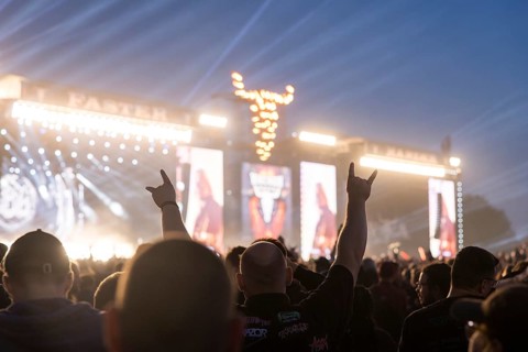 A festival visitor shows the devil's salute in front of the two main stages Faster and Harder at