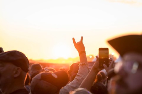 Metal greeting in front of the setting sun at the Wacken Open Air in Wacken. The traditional metal
