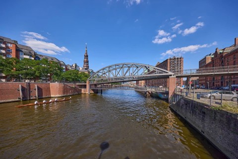 Kibbelsteg bridge over the Zollkanal with canoe and the main church St. Katharinen, Speicherstadt,