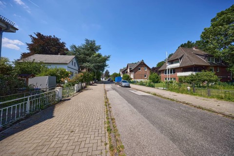 Road through a residential area with detached houses and apartment blocks in the district of