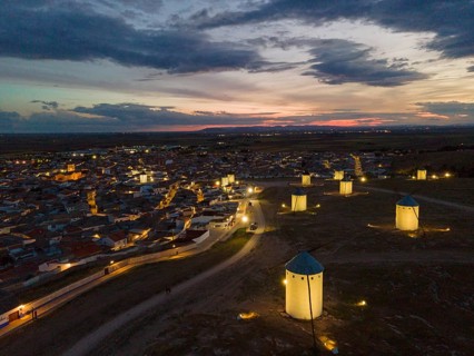 Illuminated windmills and a village in the light of dusk. The sky shows bright colours of the