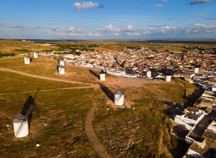 Windmills scattered on a hill near a village in sunny weather with blue skies and clouds. The