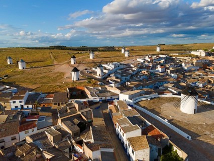 View of a village with windmills in the background in sunny weather and partly cloudy skies. Many