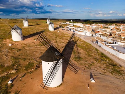 Windmills in a rural setting in sunny weather with blue sky and clouds. In the background a village