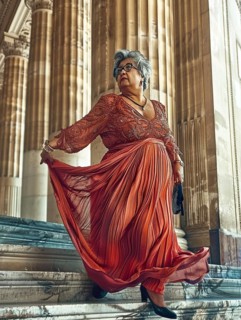Statuesque woman in an elegant red dress, poised gracefully on a grand marble staircase with