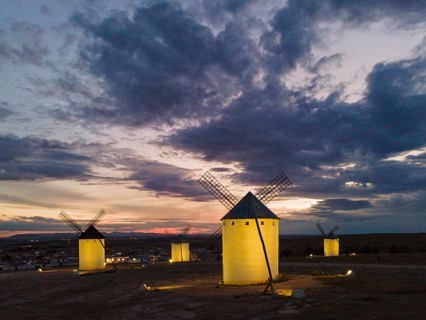 Several illuminated windmills in a rural landscape at sunset, aerial view, windmills, Campo de
