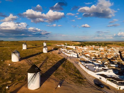 Aerial view of windmills and a village under a blue sky with clouds and long shadows, aerial view,