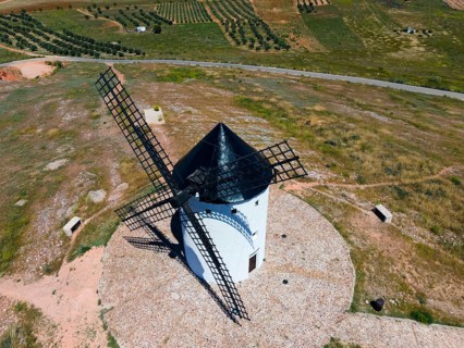 Aerial view of a white windmill in a green, rural landscape under a sunny sky, aerial view, Alcazar