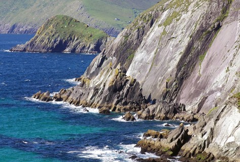 Steep cliffs with grassy areas above the rushing sea and rocky shores, Tourism, Slea Head Drive,