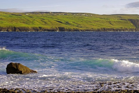 Rugged coastline with cliffs and waves, green hills in the background, Doolin, Cliffs of Moher,
