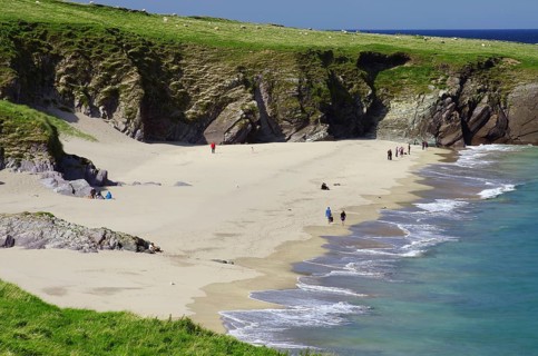 Sandy beach beach with cliffs in the background and people along the coast, Blasket Islands,