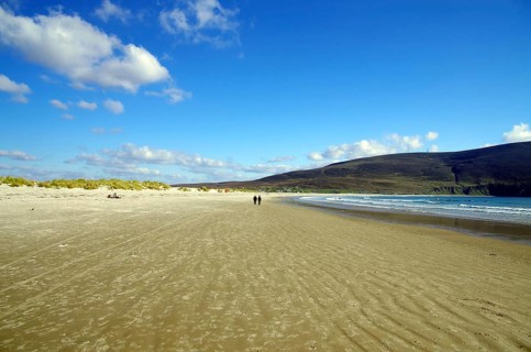 Wide sandy beach under a blue sky with few people at the water's edge, Inch Bay, Dingle, Ireland,