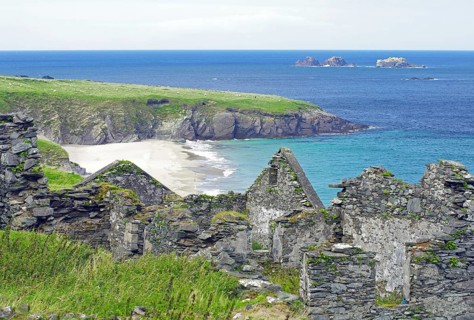 Ruins on a rocky coast with green grass and blue sea, Blasket Islands, Dunmore Head, Ireland,