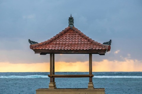 Fantastic sunrise on the beach with small temples and built as breakwaters. View of the sea as far