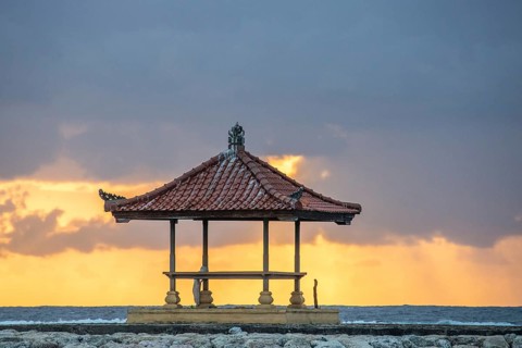 Fantastic sunrise on the beach with small temples and built as breakwaters. View of the sea as far