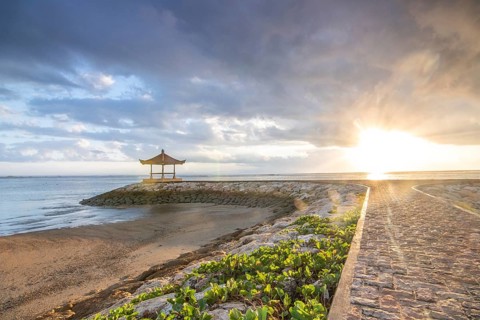 Fantastic sunrise on the beach with small temples and built as breakwaters. View of the sea as far