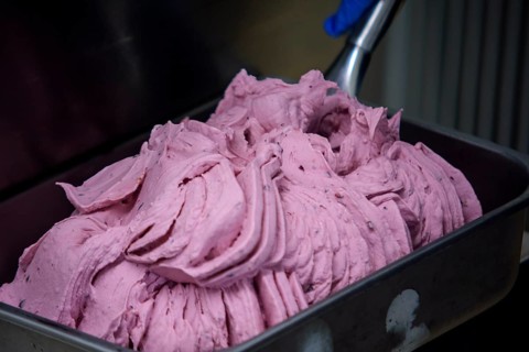 Close up of a professional ice cream machine mixing a delicious pink fruit flavor ice cream, the