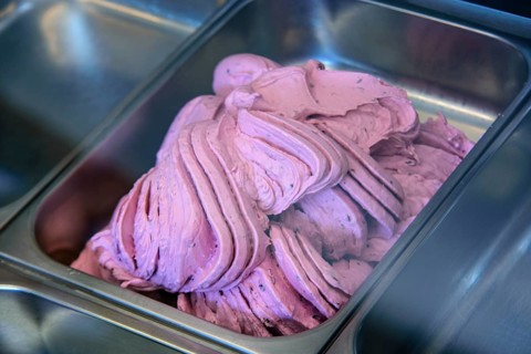 Close-up of pink ice cream being prepared in a stainless steel tray