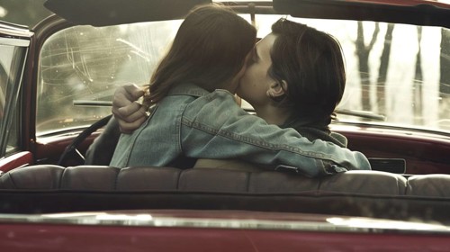 Couple kissing passionately inside a vintage car at sunset, evoking romance, AI generated