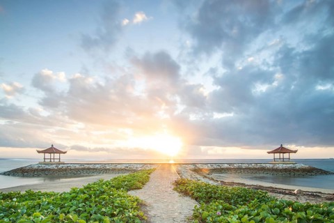 Fantastic sunrise on the beach with small temples and built as breakwaters. View of the sea as far
