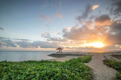 Fantastic sunrise on the beach with small temples and built as breakwaters. View of the sea as far