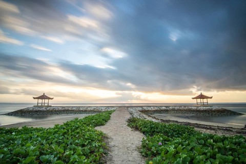 Fantastic sunrise on the beach with small temples and built as breakwaters. View of the sea as far