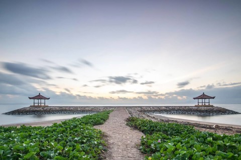 Fantastic sunrise on the beach with small temples and built as breakwaters. View of the sea as far