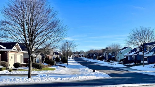 A serene suburban street in winter with snow, AI generated