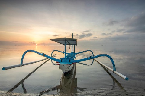 Fantastic sunrise on the beach with small temples and a traditional fishing boat, Jukung. View of