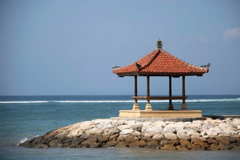 Fantastic sunrise on the beach with small temples and built as breakwaters. View of the sea as far
