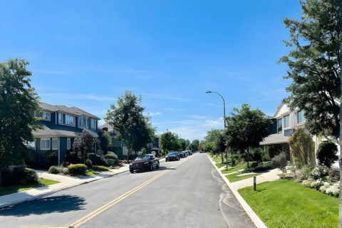 A serene suburban street with blooming plants under a bright sky, AI generated