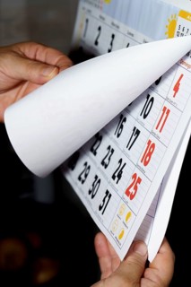 Unrecognizable woman's hands turning the pages of a calendar against a dark background