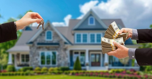 Real estate agent handing over house keys for stacks of money in front of new house