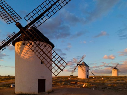 White windmills stand at sunset in an open landscape under a cloudy sky, windmills, Campo de