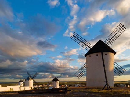 Several windmills stand in an open landscape under a dramatic sky at sunset, Windmills, Campo de