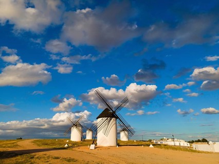 White windmills under a blue, slightly cloudy sky, with a gravel path next to them, windmills,