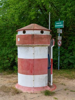 Old round red-white-ringed changing room from GDR times in the shape of a lighthouse on the shore