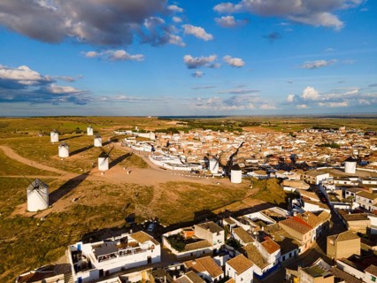 Aerial view of a village with several windmills and houses under a blue sky with clouds, aerial