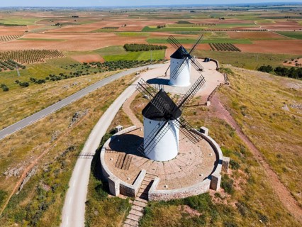 Aerial view of two white windmills with black roofs on a hill with roads and fields, aerial view,