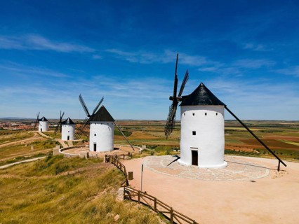 White windmills with black roofs standing in an expanse of fields and blue sky, aerial view,