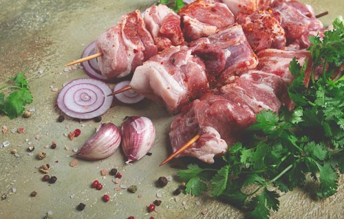 Raw pork meat, on wooden skewers, pickled kebab, with spices and herbs, on the table, top view, no