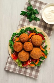 Tortillas, wrapped falafel balls, with fresh vegetables, vegetarian healthy food, on a wooden white
