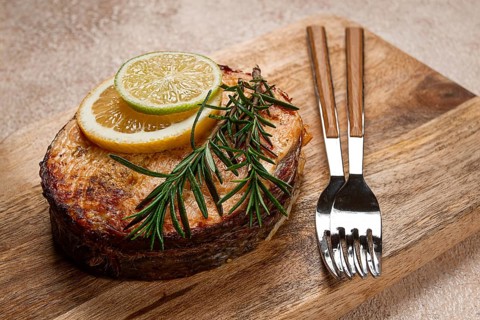 Salmon steak, fried, on a cutting board, top view, rosemary, lemon and lime, homemade, one serving,