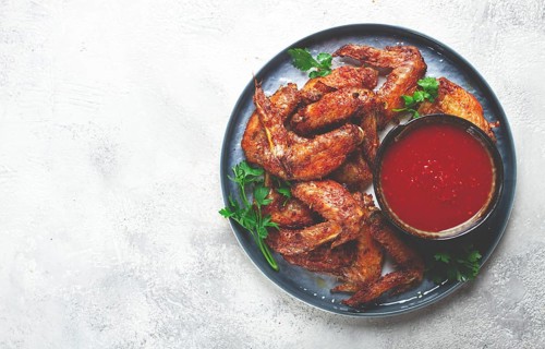 Fried in the oven, chicken wings, with spices, tomato sauce, on a plate, gray background, no