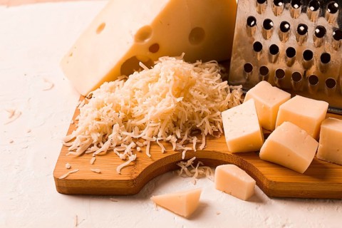 Grated cheese, Maasdam, on a cutting board, grater and cheese knife, close-up, no people