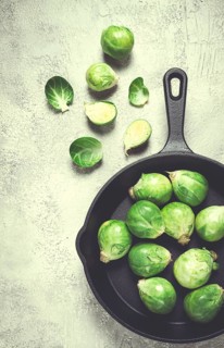 Fresh Brussels sprouts, raw, in a cast-iron pan, top view, on a gray table, no people