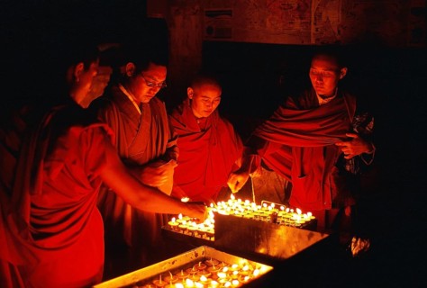 Tibetan buddhist monks and nun are lighting candles at night during the Buddha purnima festival