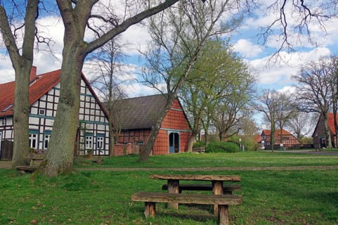 Picnic table under trees in front of half-timbered houses in a rural setting in spring, Satemin,