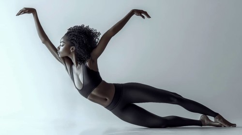 A ballerina in a black outfit gracefully extends in a side pose, showcasing elegance and balance,