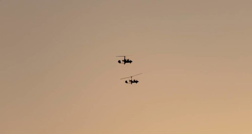 Two gyrocopters flying at sunrise, silhouettes against the morning sky, Mpumalanga, South Africa,